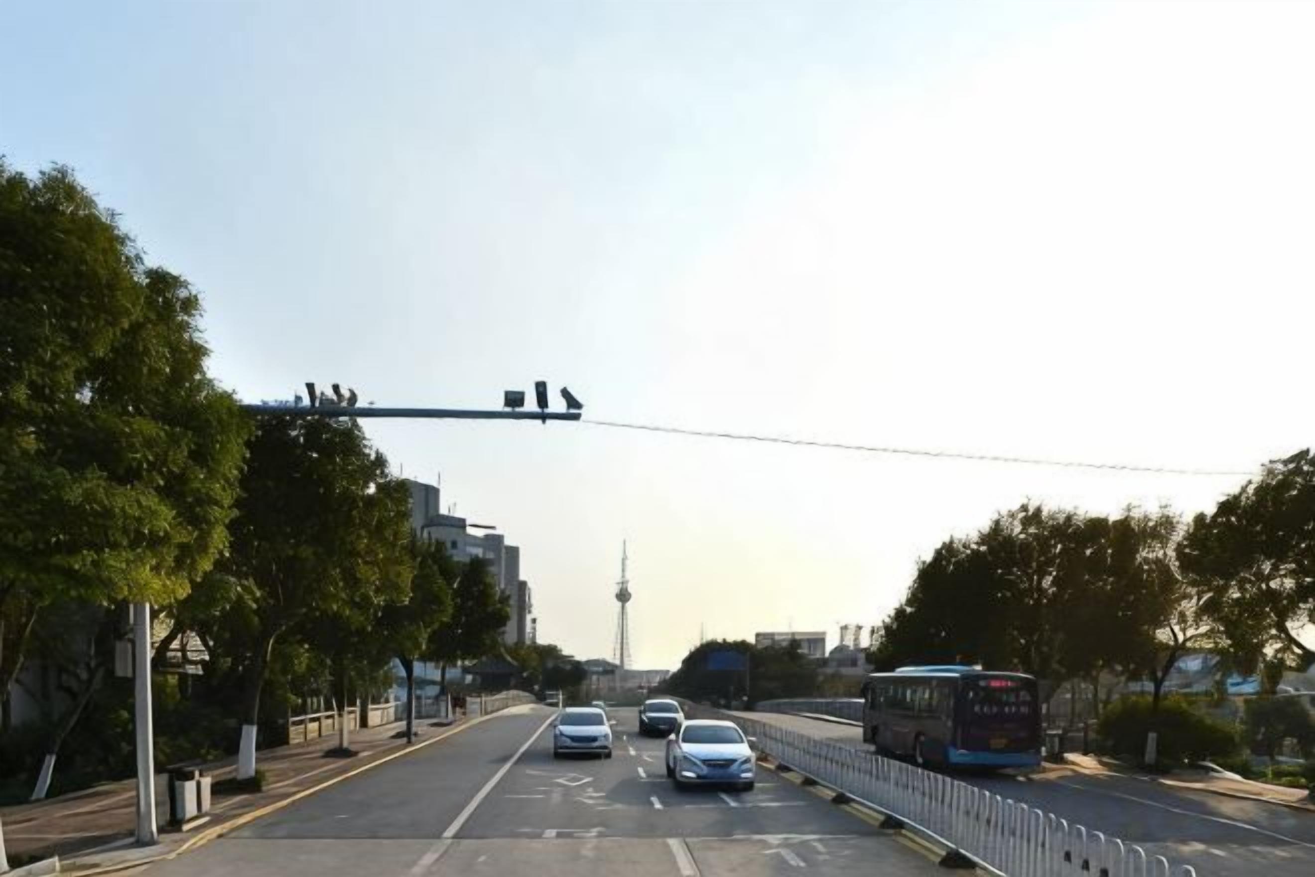 A multi-lane road with vehicles, including cars and a bus, and a pedestrian bridge.