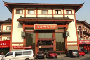 A traditional building with a large entrance and multiple cars parked in front. - Xintiandi Hotel (Haiyan)