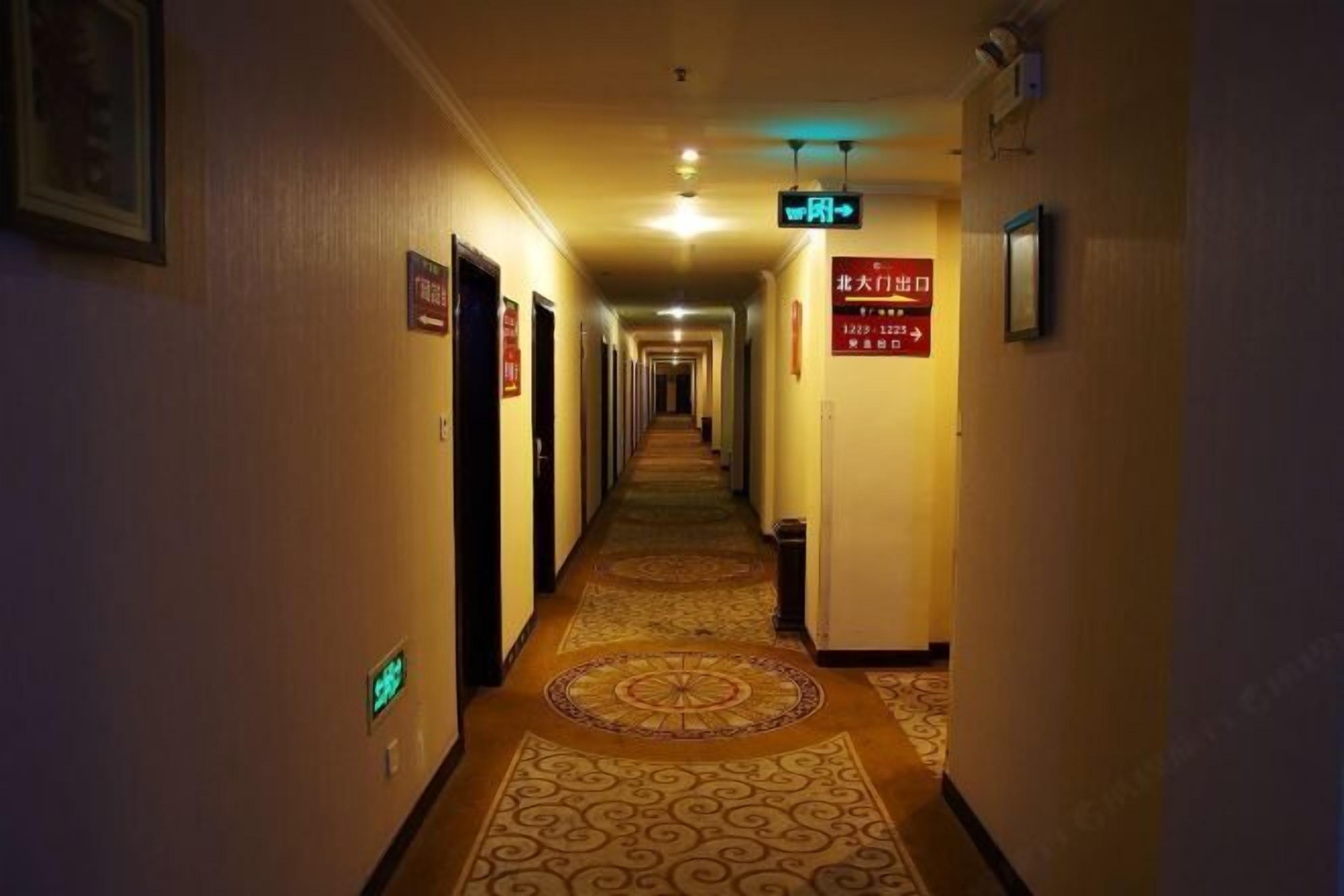 Un pasillo de hotel con piso alfombrado, puertas a ambos lados y señalización.