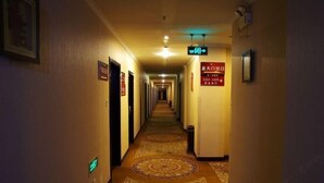 A hotel hallway with a carpeted floor, doors on both sides, and directional signs. - Xintiandi Hotel (Haiyan)