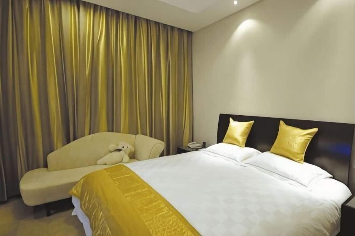 A hotel room with a bed, a bedside table, a chair, and a large window with curtains.