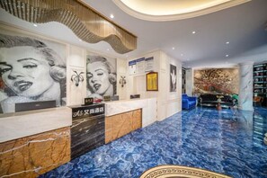 A hotel reception area with a marble floor, a reception desk, and a wall with framed artwork. - Aishang Hotel (Pubei Maoyuan Diwang International) (Pubei)