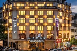 Un edificio de varios pisos con señalización iluminada, una entrada destacada y un área de estacionamiento al frente.