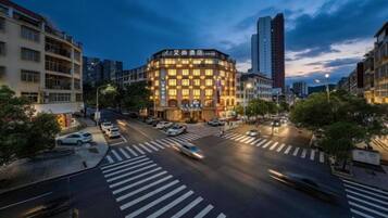 A multi-story hotel with a distinctive corner design, a pedestrian crossing, and a busy urban street.