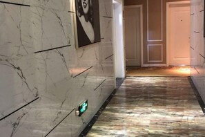 A hallway with marble walls and a patterned floor, leading to a door. - Aishang Hotel (Pubei Maoyuan Diwang International) (Pubei)