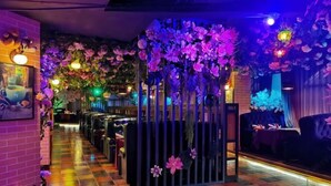 A corridor with a checkered floor, a black metal gate, and walls adorned with hanging flowers. - Aishang Hotel (Pubei Maoyuan Diwang International) (Pubei)