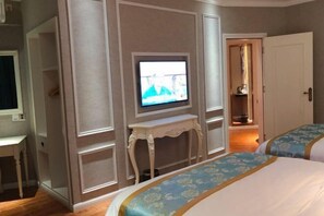 A hotel room with a television mounted on a wall, a bed with floral bedding, and a small table. - Aishang Hotel (Pubei Maoyuan Diwang International) (Pubei)