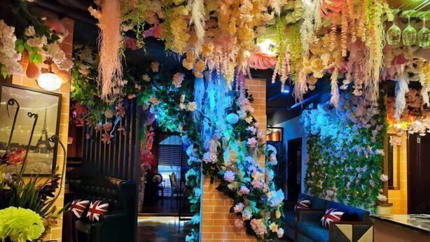 A hotel lobby with a floral archway, a checkered floor, and a seating area with a Union Jack pillow. - Aishang Hotel (Pubei Maoyuan Diwang International) (Pubei)