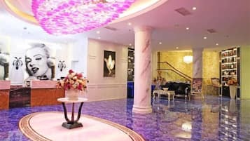Um hall de entrada com balcão de recepção, escada e lustre.