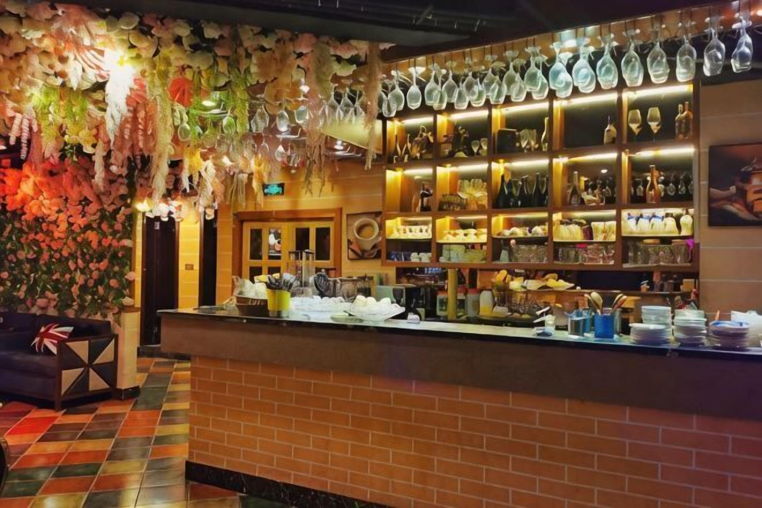 A bar area with a brick counter, shelves of bottles, and hanging glassware.