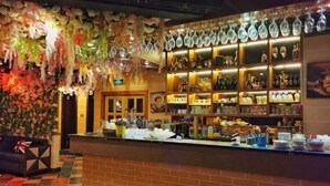 A bar area with a brick counter, shelves of bottles, and hanging glassware. - Aishang Hotel (Pubei Maoyuan Diwang International) (Pubei)