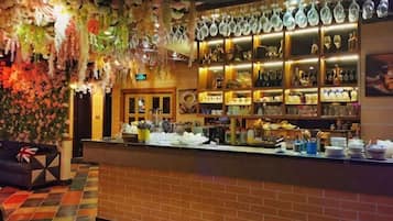 A bar area with a brick counter, shelves of bottles, and hanging glassware.
