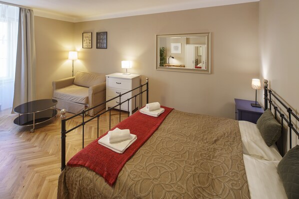 A hotel room with a bed, a chair, a desk, a mirror, and a lamp. - OLD TOWN-3 BEDROOM 3 BATHROOM TEMPLOVA (Hlavní mesto Praha)