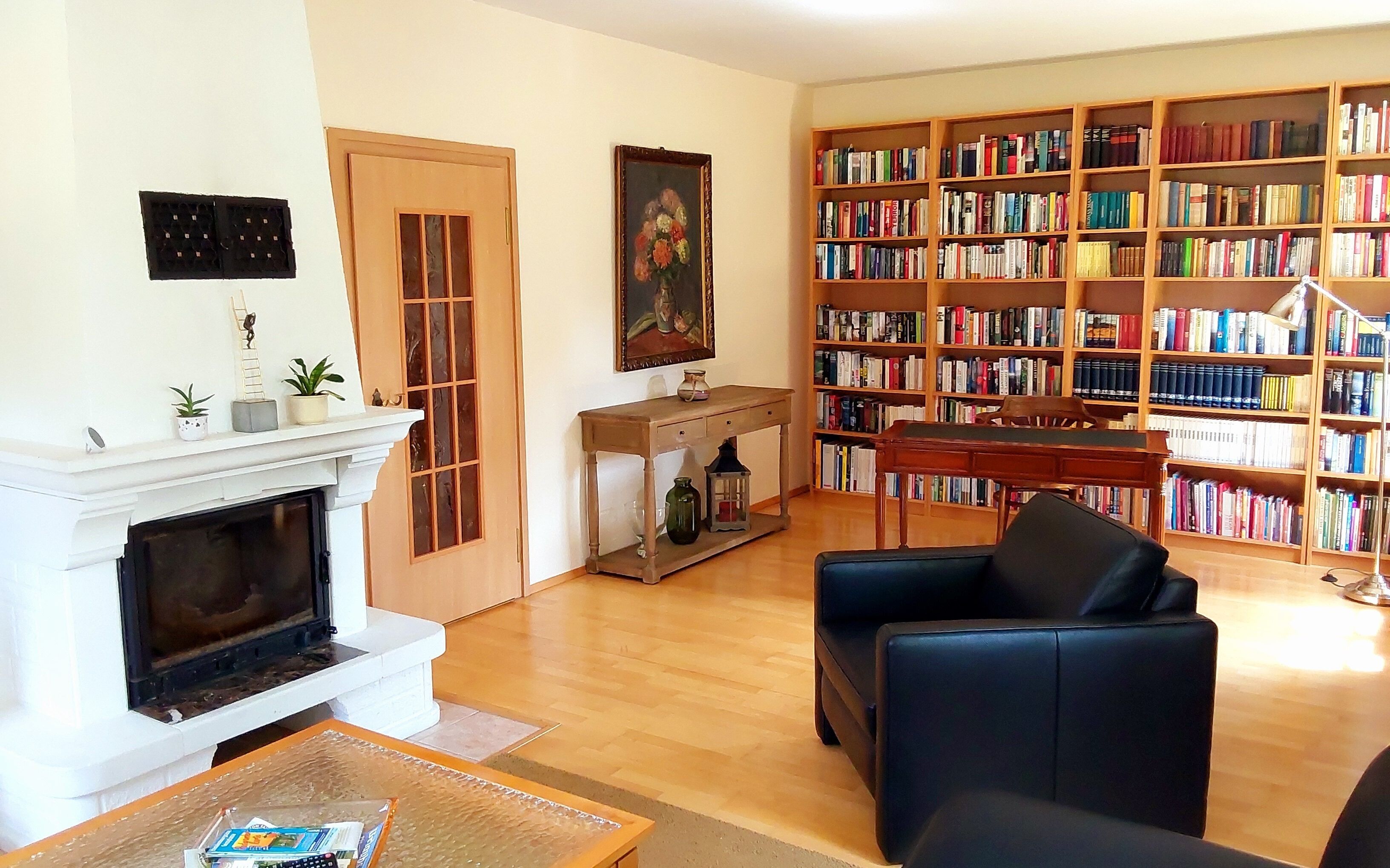 A living room with a fireplace, a bookshelf, and a black leather armchair.