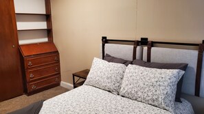 Cozy retreat with a neatly made bed, dresser, and nightstand.