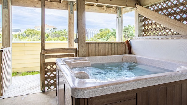 Ein Whirlpool in einer Holzterrasse mit Blick auf Häuser und Bäume.