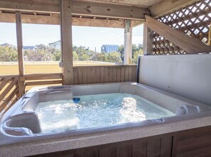 Un jacuzzi con cubierta de madera y vistas a edificios al fondo.