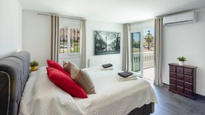 Ein Schlafzimmer mit Bett, Kommode und Fenster mit Außenblick.