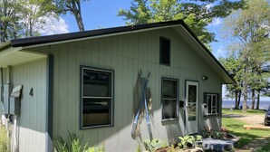 A single-story house with a sloped roof, a front door, and a small porch area. - 4 seasons of adventures on Indian Lake/Sunset View Resort/Unit#4 (Manistique)
