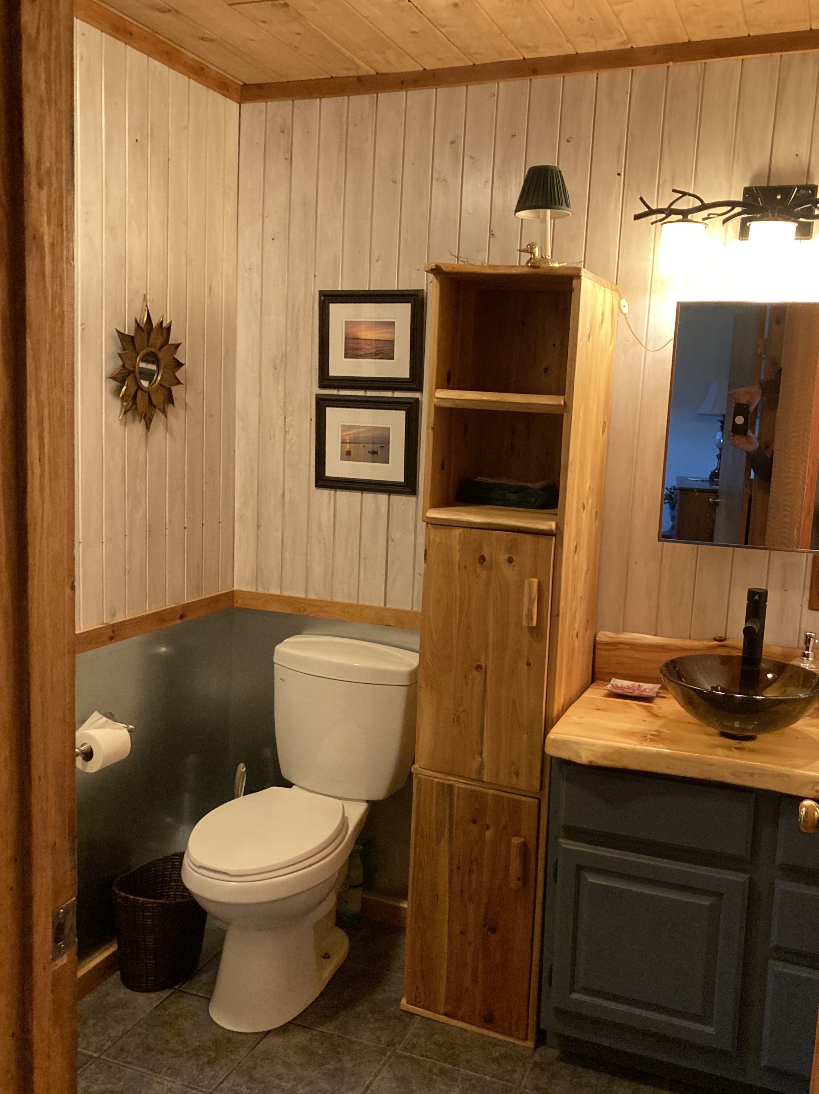 Un baño con tocador de madera, inodoro y lavamanos.