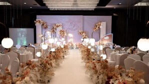 Ein Festsaal mit einer zentralen Gänge, gesäumt von Blumenschmuck und runden Tischen.