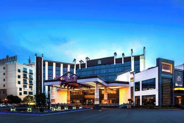 Ein modernes Hotel mit einem markanten Eingang, großen Fenstern und einer gut beleuchteten Fassade.