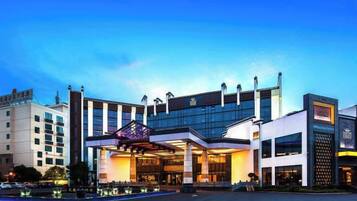 A hotel with a modern glass facade, a prominent entrance, and a parking lot.