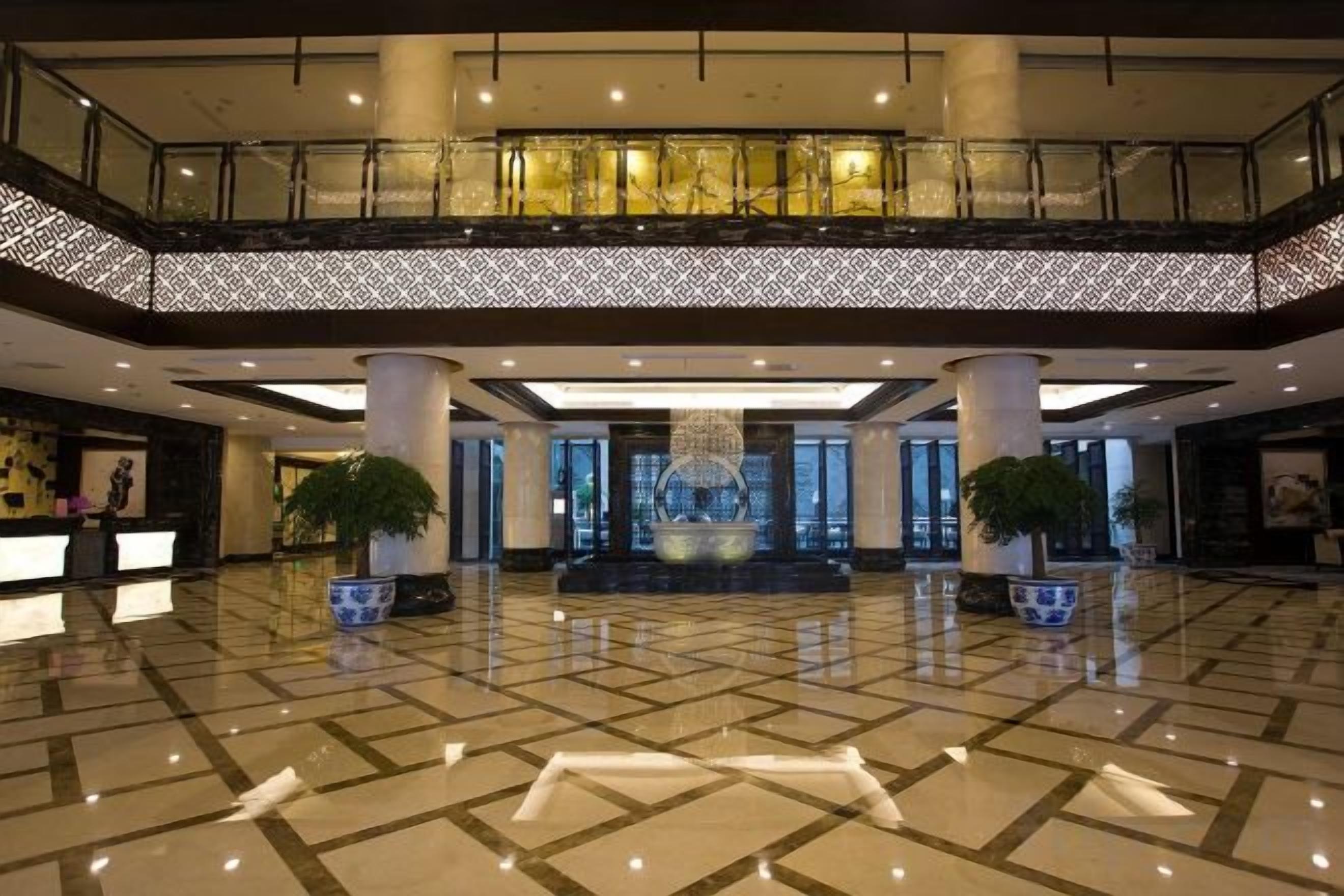 A spacious lobby with a high ceiling, a reception desk, and a central decorative fountain.