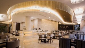 Ein geräumiges Restaurant mit gewölbter Decke und Kronleuchtern, das eine zentrale Bar und verschiedene Sitzgelegenheiten bietet.