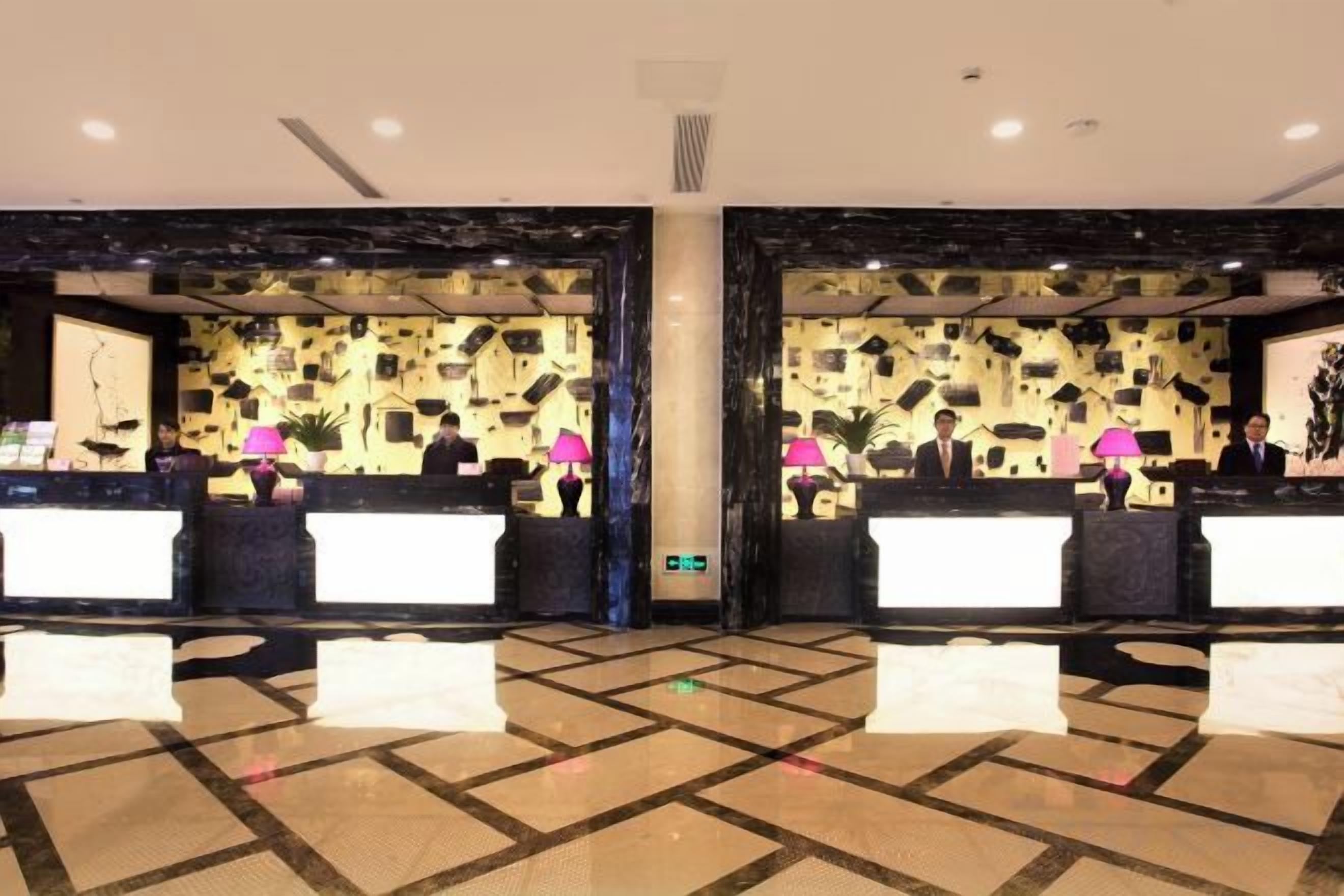 A reception area with two reception desks, a patterned wall, and a check-in counter.