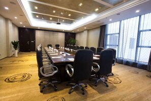 Un salón de conferencias con una larga mesa, sillas y un proyector.