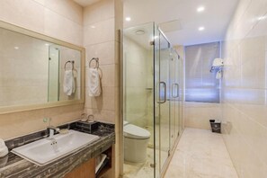 Une salle de bain moderne avec une douche à parois de verre, un grand miroir et un comptoir en marbre.
