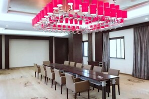 Un salón de conferencias con una larga mesa, sillas y una lámpara de araña moderna.