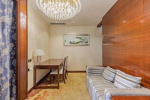 Une pièce avec un mur lambrissé, une table à manger avec des chaises, un canapé et un lustre.