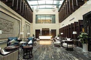 Eine geräumige Lobby mit hoher Decke, einer zentralen Treppe und Sitzbereichen.