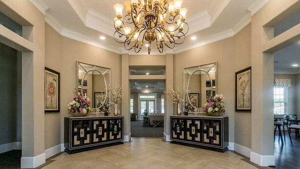 Eine geräumige Lobby mit einem beeindruckenden Chandelier, symmetrischen Spiegeln und dekorativen Vasen.