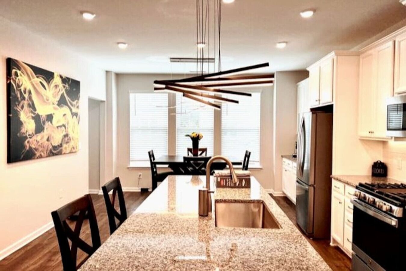 A modern kitchen with a central island, stainless steel appliances, and a dining area with a view to the outdoors.