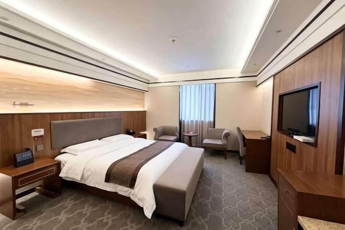 Ein Hotelzimmer mit einem großen Bett, einem Schreibtisch, einem Fernseher und einer Sitzecke.