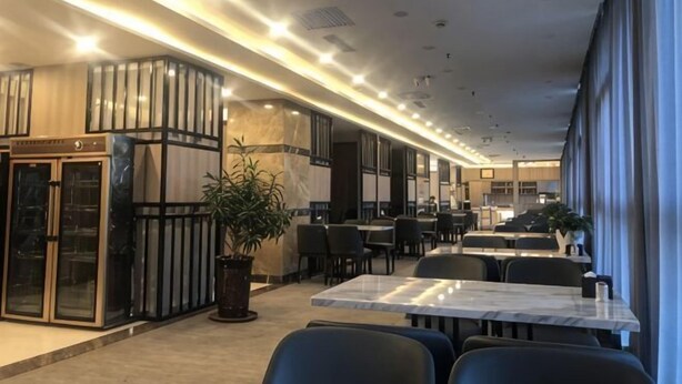 A modern hotel lobby with marble flooring, a reception desk, and a seating area with tables and chairs. - Junrui Garden Hotel (Qianguo)