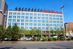 A multi-story hotel with a grid of windows, a flat roof, and a parking lot in front. - Junrui Garden Hotel (Qianguo)