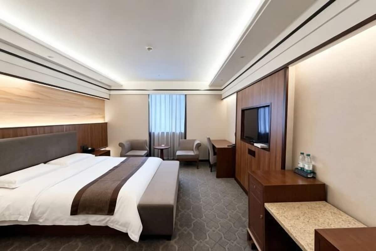 Ein Hotelzimmer mit Bett, Sitzgelegenheit, Fernseher und Minibar.