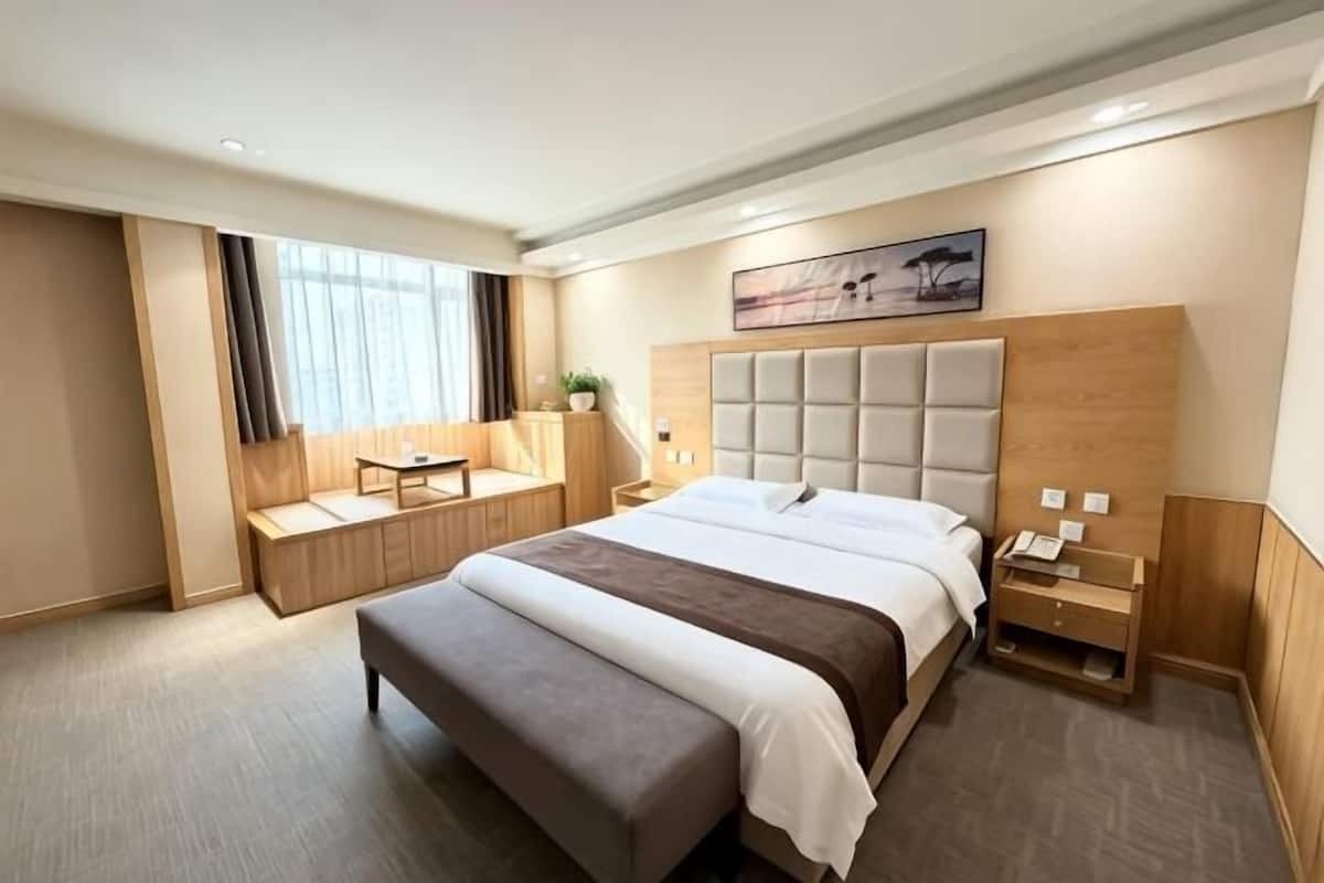 Ein Hotelzimmer mit einem großen Bett, einer Sitzecke, einem Schreibtisch und einem Bild an der Wand.