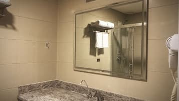 A bathroom with a sink, mirror, and hair dryer.