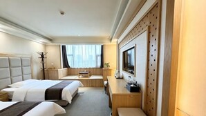 A hotel room with two beds, a desk, a TV, and a coat rack. - Junrui Garden Hotel (Qianguo)
