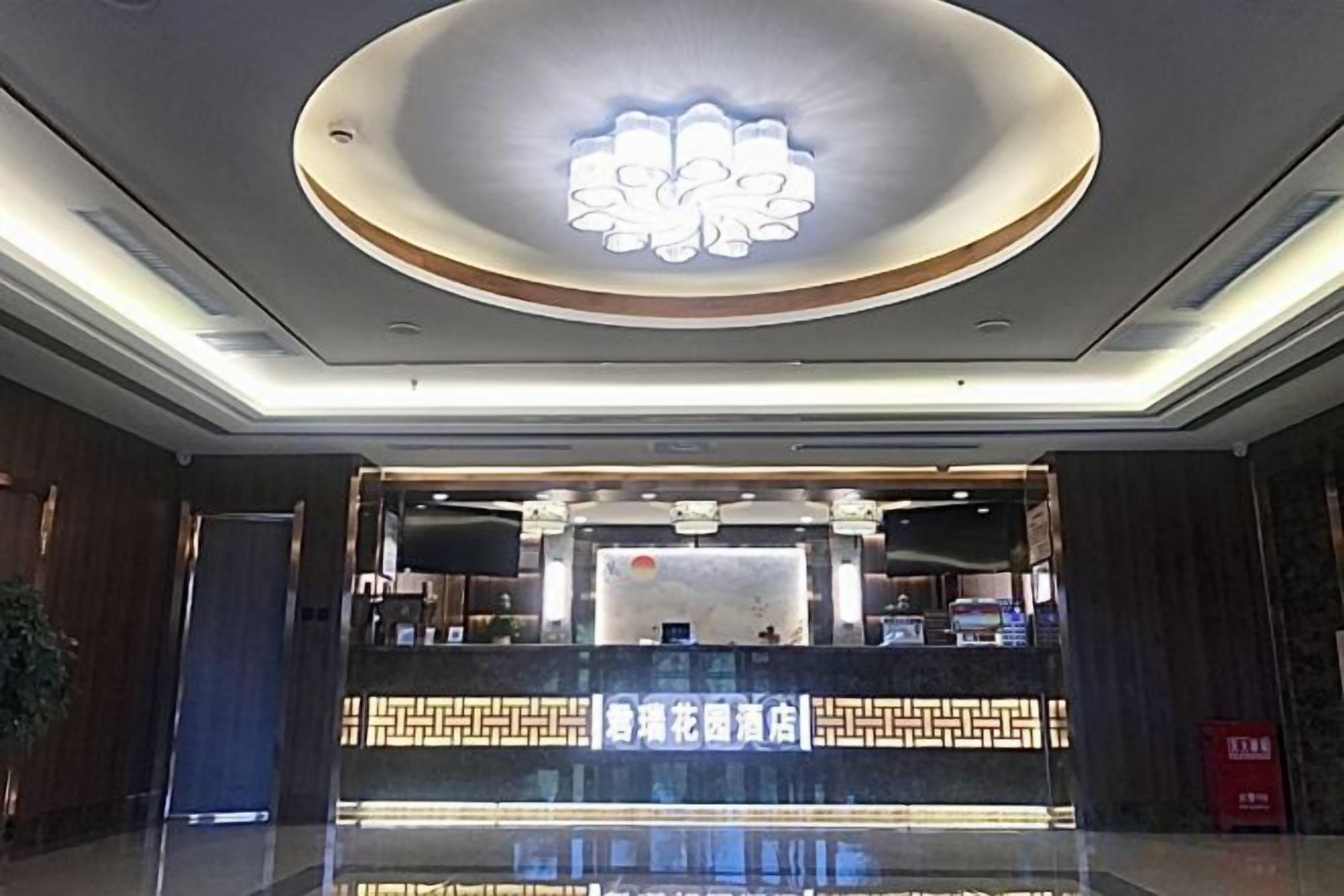 A hotel reception area with a modern design, featuring a reception desk, a decorative ceiling light, and a reception counter with a patterned design.
