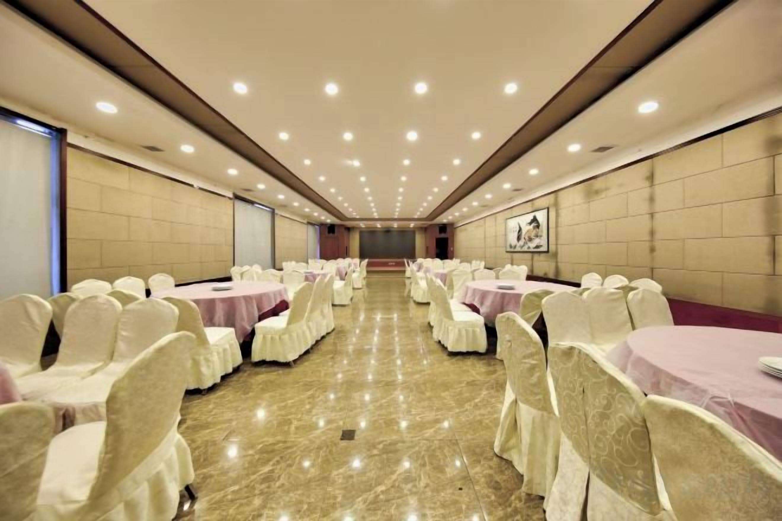 Sala de conferência com mesas e cadeiras redondas, piso de mármore e uma ampla vista para o fundo.