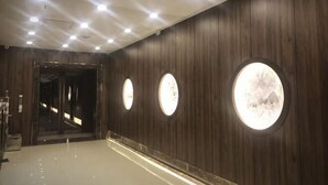 A hallway with wooden paneling, circular wall sconces, and a reflective floor. - Junrui Garden Hotel (Qianguo)
