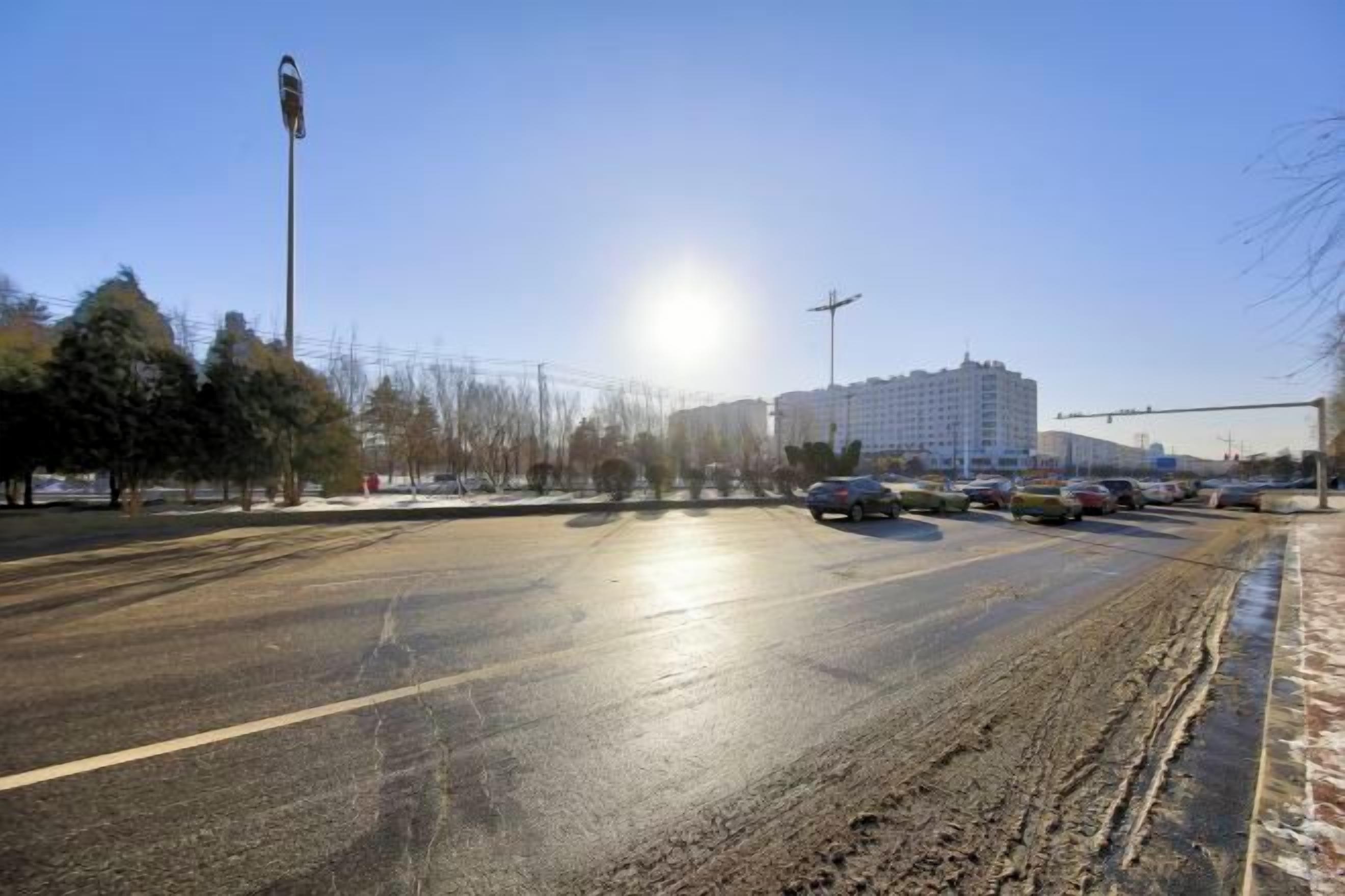 Eine breite Straße mit mehreren Fahrbahnen, wolkenloser Himmel und entfernte Gebäude.