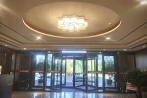 A hotel entrance with revolving doors, a chandelier, and a reception desk.