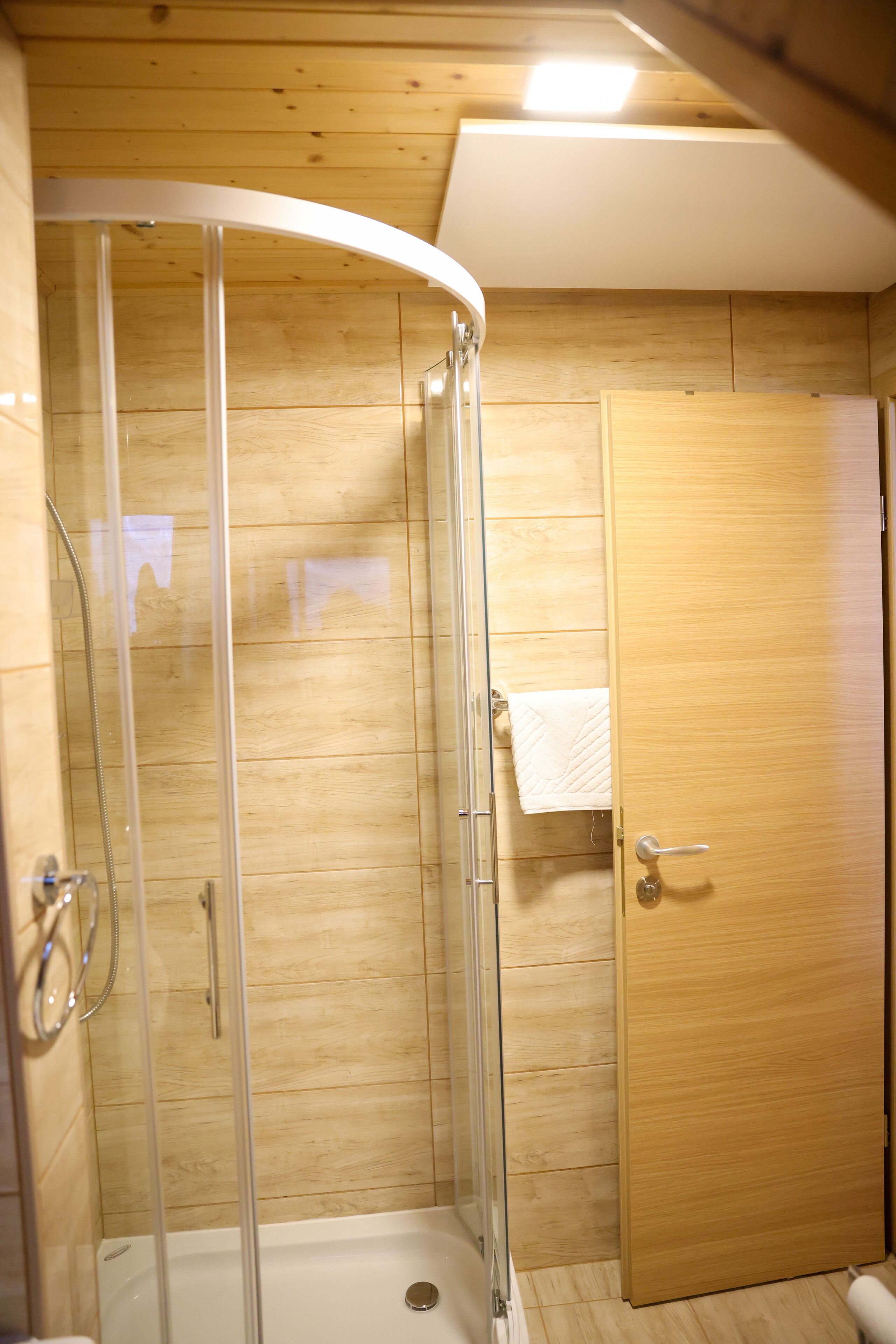 Un espace de douche doté d’une porte en verre, de murs en bois et d’une porte en bois.